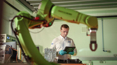 An engineer from the University of Sheffield AMRC looking at a tablet in front of a robotic arm used in manufacturing