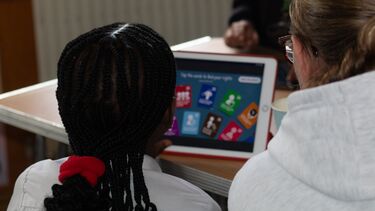 A schoolgirl plays a game on a tablet
