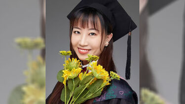 Mingyue Zhao in graduation dress, holding a bunch of yellow flowers