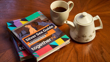 A book, cup of tea and teapot on a table.