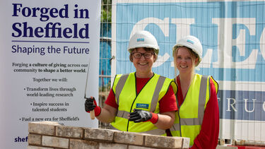 Two women in hard hats and high vis jackets laying a ceremonial brick for the new SITraN building expansion