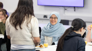 A Grantham scholar sitting at a desk chatting with other scholars