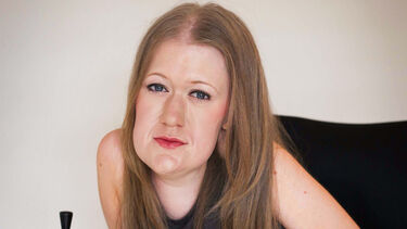Headshot of a person with long straight hair parted in the middle