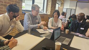 Group of academics sitting at a table with papers and laptops