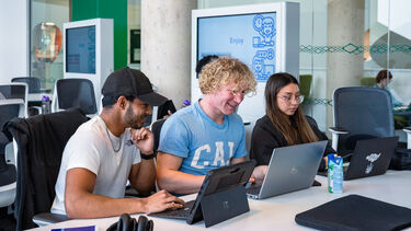 Three students working on laptops