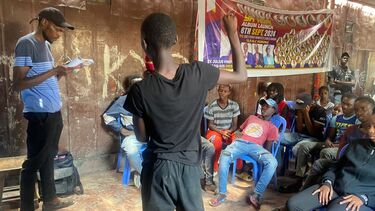 A group of locals from Mathare sitting down in a community room, listening to a speaker