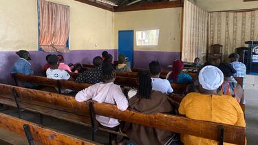A film screening of the documentary taking place inside a community hall and attend by the local people living in Mathare