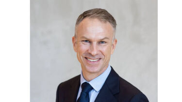 Headshot of a person in a suit against a plain background