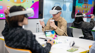 Students using virtual reality headsets and controllers in a workshop space
