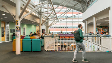 Person wearing a backpack, walking through an atrium area.