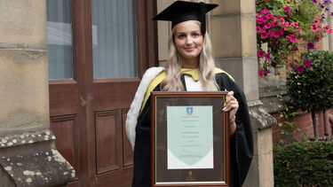 Anna Langston in graduation gown with certificate 