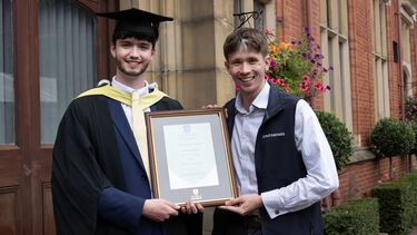 James Pennington in graduation gown with certificate 