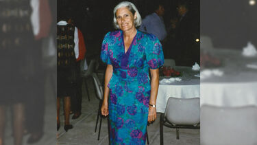 Maureen at a party in the 1980-90s, smiling and wearing a patterned turqouise dress