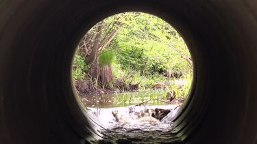 Inside of a water pipe, water cascading into a river