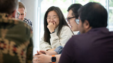 A group of young people sitting together smiling and talking.