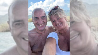 A selfie of David Brown and his wife Carmel smiling warmly beside a sunny lake in 2023