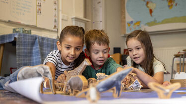 Three children playing with wooden animals