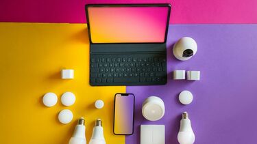 Laptop, mobile phone and light bulbs on a colourful background