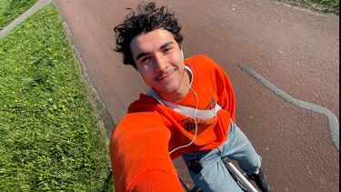 young man on bike taking a selfie wearing an orange shirt 