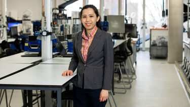 Researcher in the Diamond wearing a grey blazer and colourful shirt, smiling