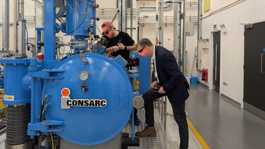 Engineers operate and observe an alloy being created in a vacuum induction furnace