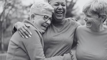 Three laughing women embrace
