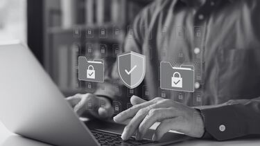 A person uses a laptop with images of padlocked files in the foreground