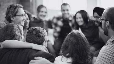 A group of smiling people gather in a huddle.