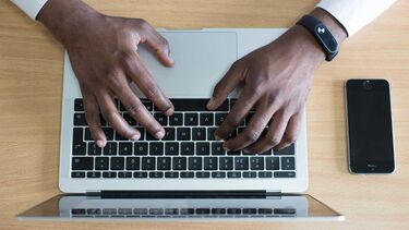 Hands typing on a laptop