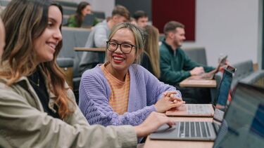 Students with laptops in teaching space