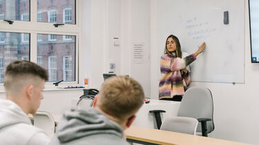 Lecturer explaining a maths problem on a whiteboard