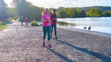Runner on path by lake in sunny weather