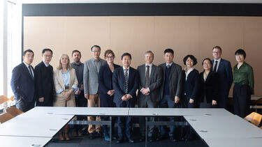 A group of staff from the universities of Sheffield and Tongi stand together in a meeting room and smile towards the camera.