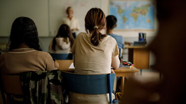 Two girls viewed from behind sat in a school classroom