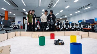 A group of computer science students are trying the robot in front of the robot arena
