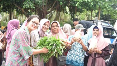 Grantham scholar, Eva Andriani, and her supervisor, Olga Cam, posing with fresh vegetables bought from a street food vendor in Indonesia