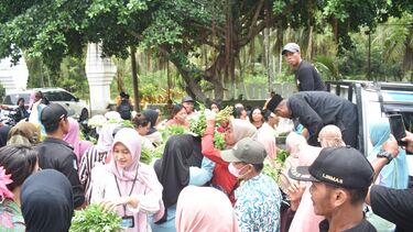 A large group of people buying produce from a street vendor in Indonesia