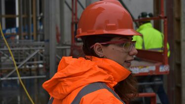 woman with red hard hat and orange reflective jacket