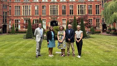 Three University of Sheffield colleagues stand alongside two colleagues from Griffith University in the Firth Court gardens and smile towards the camera.