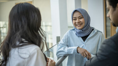 Three people leaning against a balcony