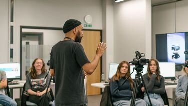 Man presenting to a group of students, in front of a camera