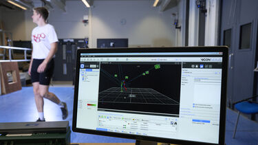Computer screen showing data with a patient wearing leg sensors in the background