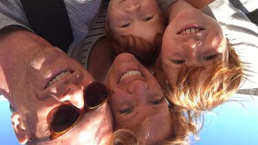 Kate and her family (husband and two kids) smiling at the camera.