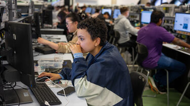 Students are working in Electronics and Control Lab. A girl student is looking at the screen with some circuits on the desk.