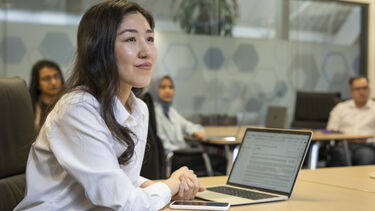 A female management school student sitting in a seminar with a laptop on her desk