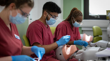 Two students wearing masks and practising on phantom heads in the CSLE