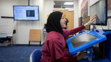A student points to a screen in the VR Suite