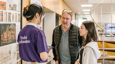 A student ambassador talks to visitors at open day.