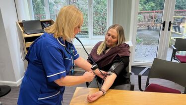 A woman getting her blood pressure checked by a nurse