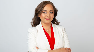 Aarti Samani stands with her arms folded. She is wearing a white jacket.